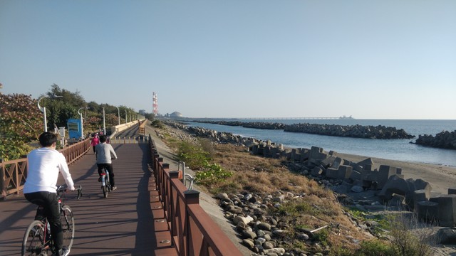 黃金海岸的風景。左邊有人騎腳踏車和走路，右邊有海，天氣很好