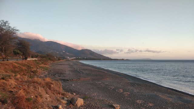 在黃昏的光線拍的照，山跟沙灘跟海，還有一些雲