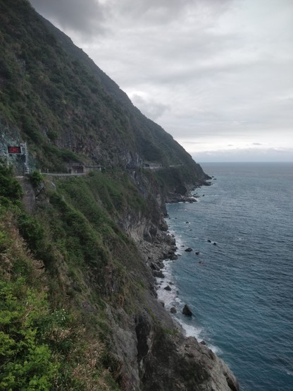 從台9丁線拍的山崖，陰天，左邊是山，右邊是海，還有在山中間透過幾個隧道的公路