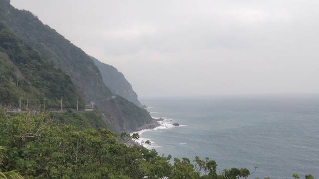 從台9丁線拍的山崖，陰天，左邊是山，右邊是海，還有公路在山中間