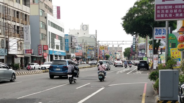 台南市西門路的照片，天氣陰天，在路上有一些汽車跟機車，兩邊有蠻多店的牌子